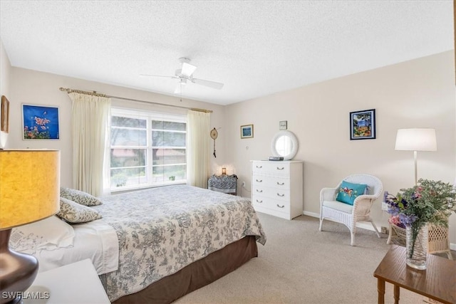 bedroom with ceiling fan, light carpet, and a textured ceiling