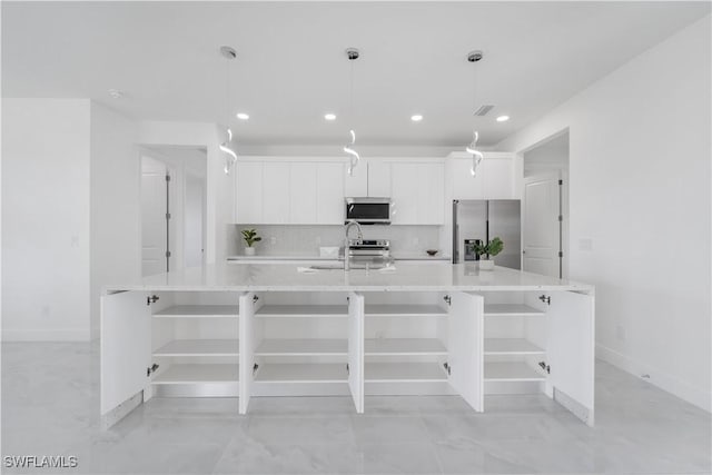 kitchen with white cabinetry, stainless steel appliances, decorative light fixtures, and a large island with sink