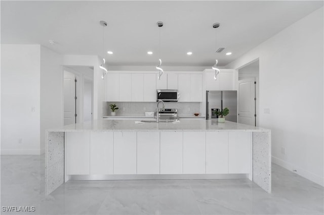 kitchen featuring a large island, appliances with stainless steel finishes, decorative light fixtures, and light stone countertops