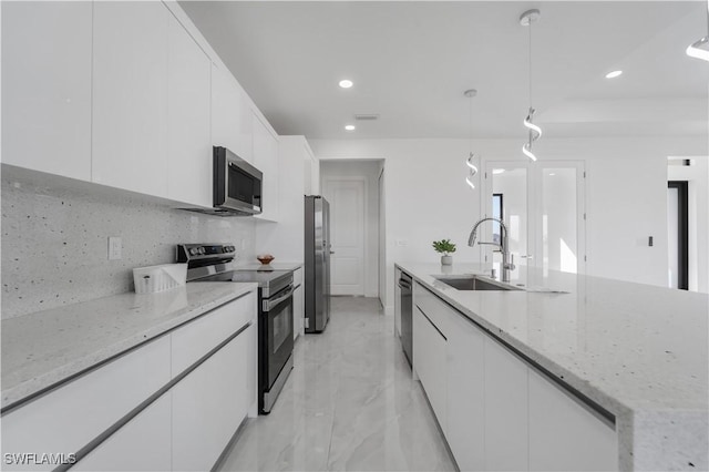 kitchen featuring light stone counters, stainless steel appliances, hanging light fixtures, and white cabinets