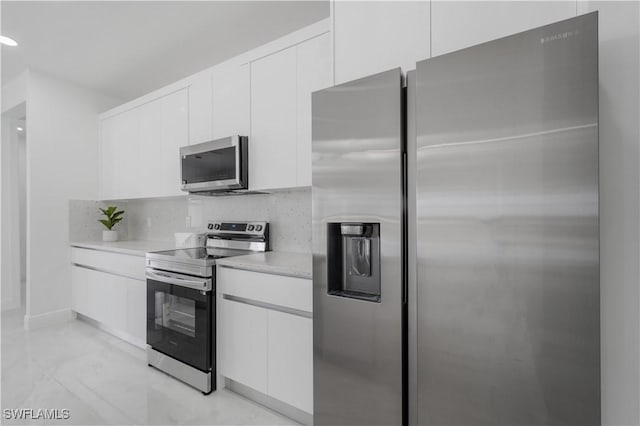 kitchen with appliances with stainless steel finishes, white cabinets, and backsplash