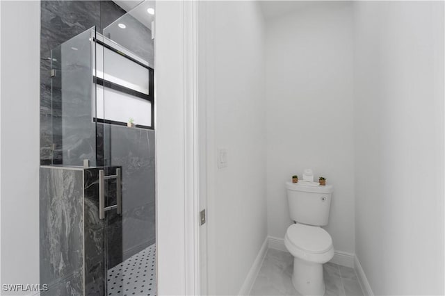 bathroom featuring a shower with shower door and toilet