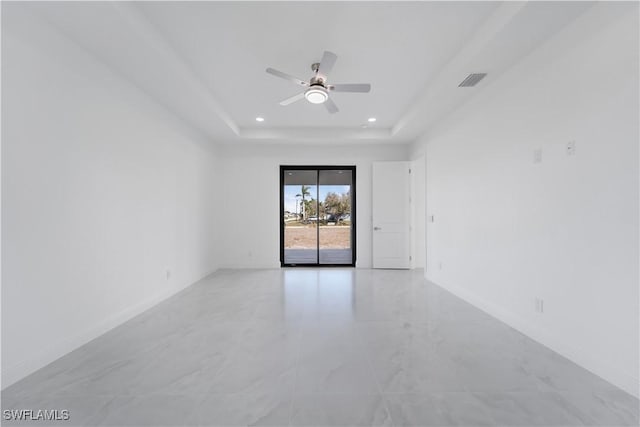 spare room with a tray ceiling and ceiling fan