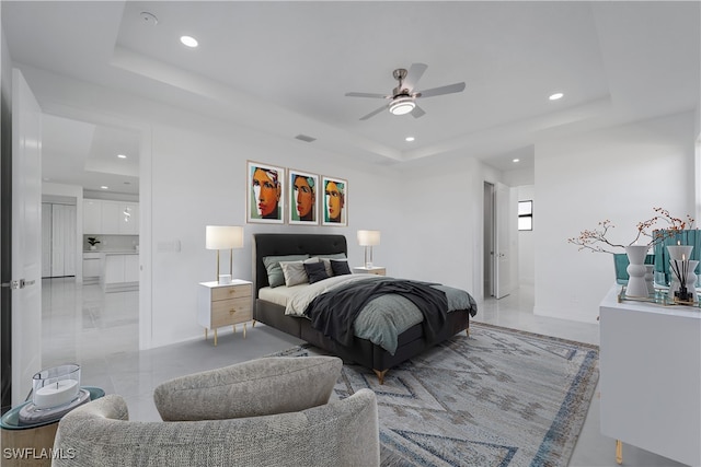 bedroom with ensuite bath, a raised ceiling, and ceiling fan