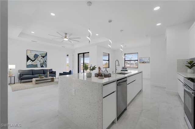 kitchen with appliances with stainless steel finishes, decorative light fixtures, an island with sink, sink, and white cabinets