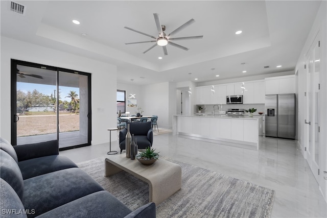 living room with a raised ceiling and ceiling fan