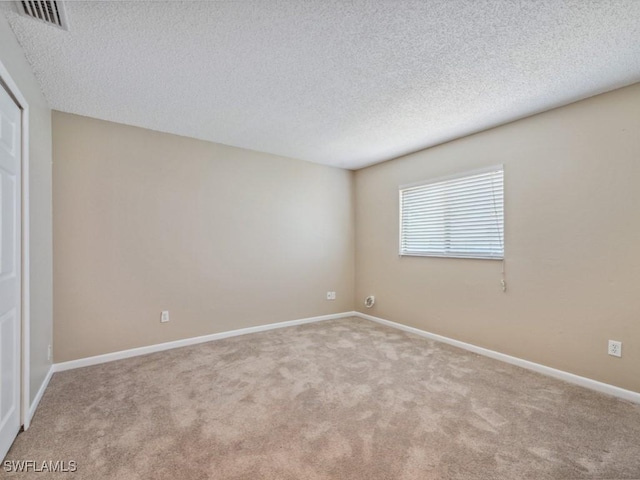 unfurnished room with light colored carpet and a textured ceiling