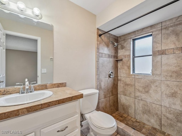 bathroom featuring tiled shower, vanity, and toilet