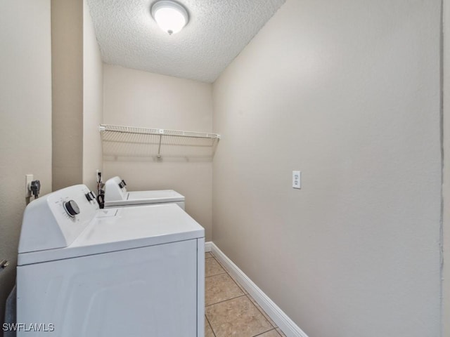 washroom with a textured ceiling, washer and dryer, and light tile patterned floors