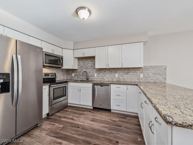 kitchen with dark hardwood / wood-style floors, white cabinetry, sink, stainless steel appliances, and light stone countertops