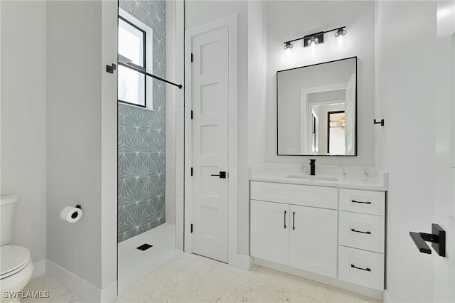 bathroom featuring vanity, a tile shower, and toilet