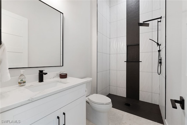 bathroom featuring tiled shower, vanity, and toilet