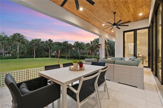 patio terrace at dusk featuring ceiling fan, outdoor lounge area, and a lawn