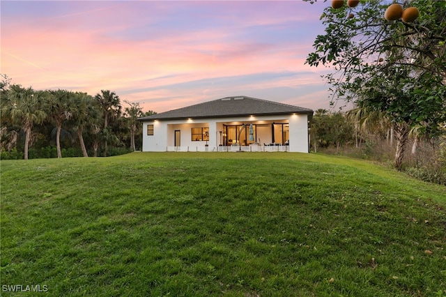 back house at dusk featuring a yard