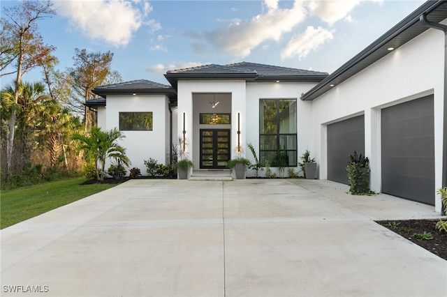 rear view of house featuring a garage and french doors