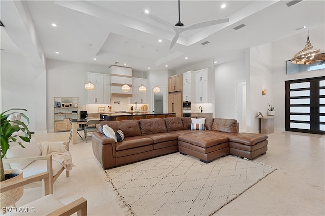 living room featuring a towering ceiling, ceiling fan, and a tray ceiling