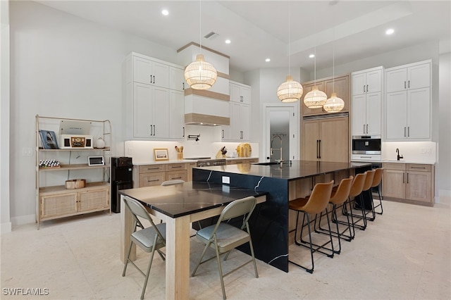 kitchen featuring a kitchen bar, sink, white cabinetry, pendant lighting, and a large island