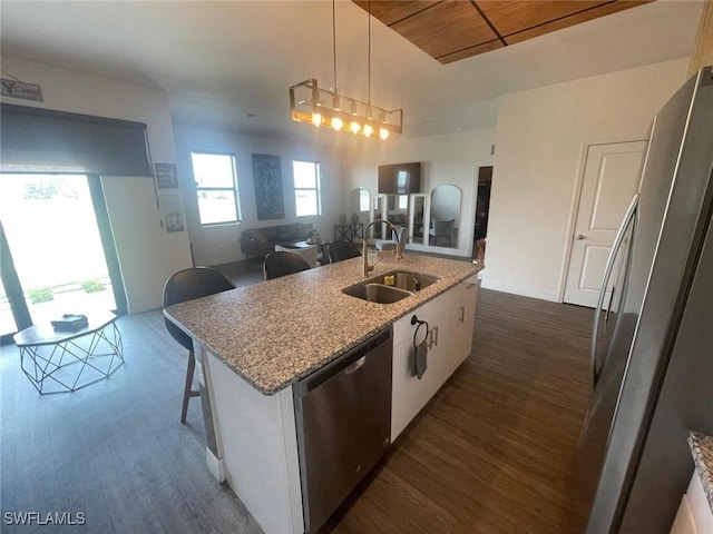 kitchen with appliances with stainless steel finishes, decorative light fixtures, sink, white cabinets, and a kitchen island with sink