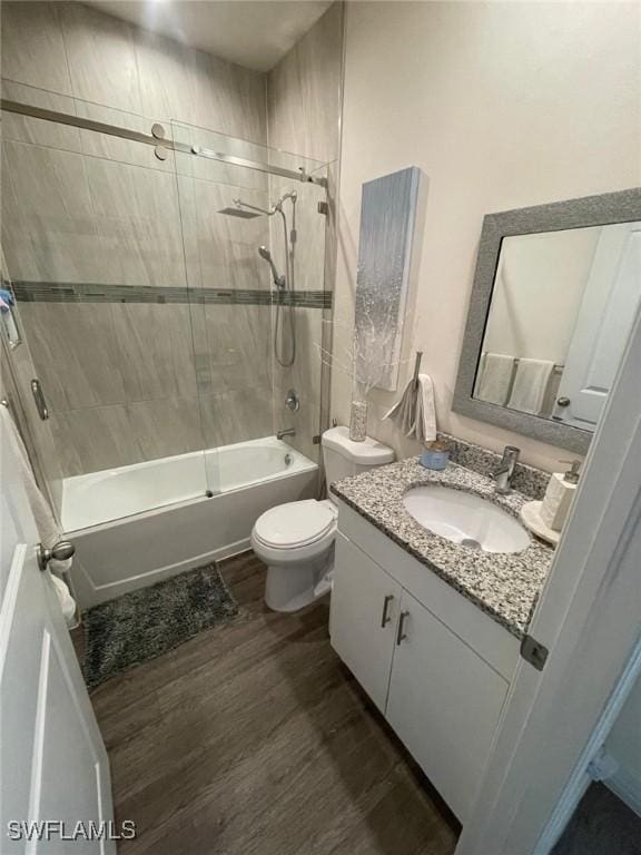 full bathroom with vanity, hardwood / wood-style flooring, toilet, and tiled shower / bath