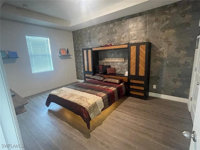 bedroom with hardwood / wood-style flooring and a raised ceiling