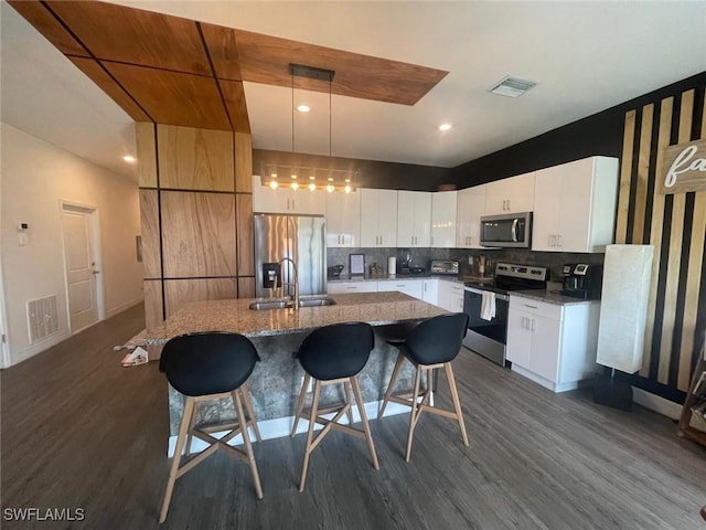 kitchen featuring stainless steel appliances, a kitchen island, hanging light fixtures, and white cabinets