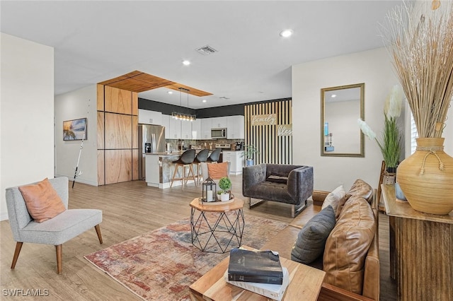 living room featuring visible vents, light wood-style flooring, recessed lighting, and a chandelier