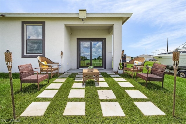 rear view of house with a lawn and stucco siding