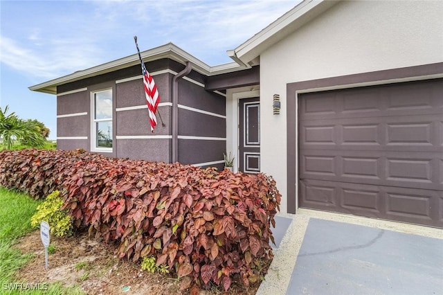 entrance to property with a garage and stucco siding