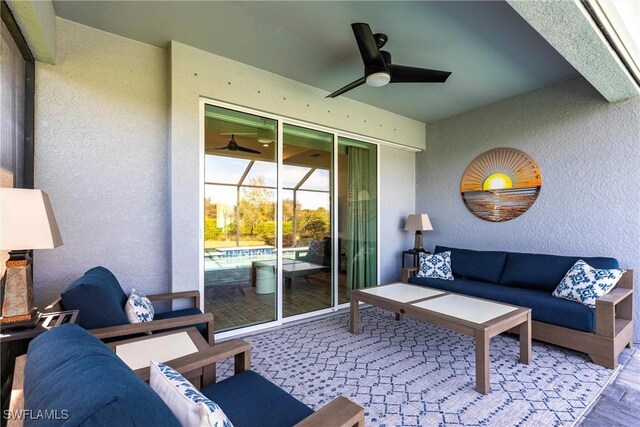 living area with ceiling fan, a textured wall, a sunroom, and light wood-style floors