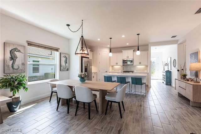 dining space featuring wood tiled floor, a healthy amount of sunlight, visible vents, and recessed lighting