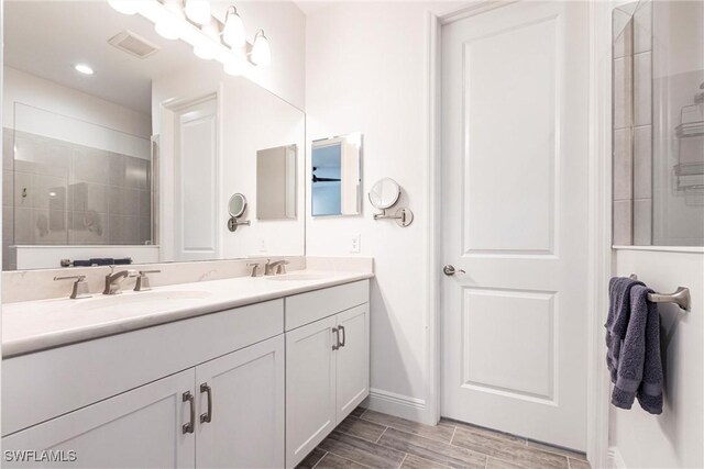 full bath with double vanity, a sink, visible vents, and baseboards