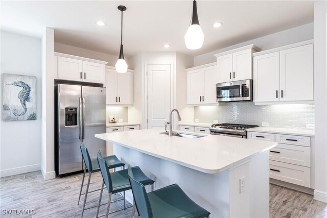 kitchen featuring white cabinetry, stainless steel appliances, a sink, and pendant lighting