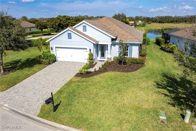 single story home with decorative driveway, a tile roof, stucco siding, a front yard, and a garage