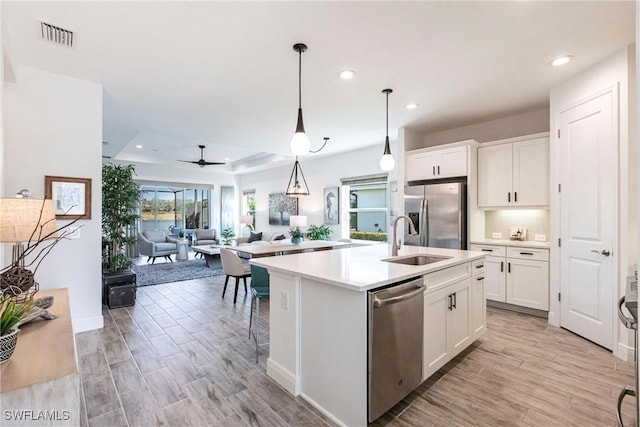 kitchen featuring stainless steel appliances, sink, an island with sink, and white cabinets