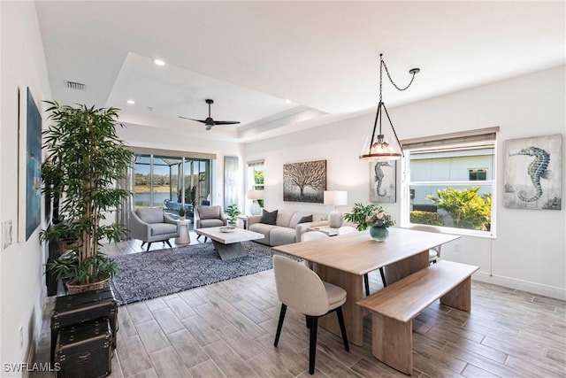 dining room featuring hardwood / wood-style flooring, ceiling fan, and a raised ceiling