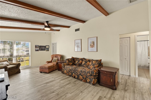 living room with lofted ceiling with beams, ceiling fan, a textured ceiling, and light hardwood / wood-style floors