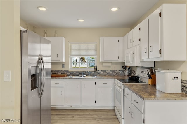 kitchen with sink, white appliances, white cabinetry, light hardwood / wood-style floors, and decorative backsplash