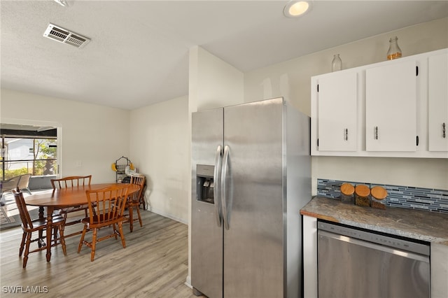 kitchen with appliances with stainless steel finishes, white cabinetry, light hardwood / wood-style floors, a textured ceiling, and decorative backsplash