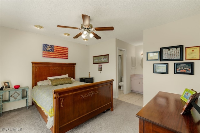 bedroom with light carpet, ceiling fan, a textured ceiling, and ensuite bathroom