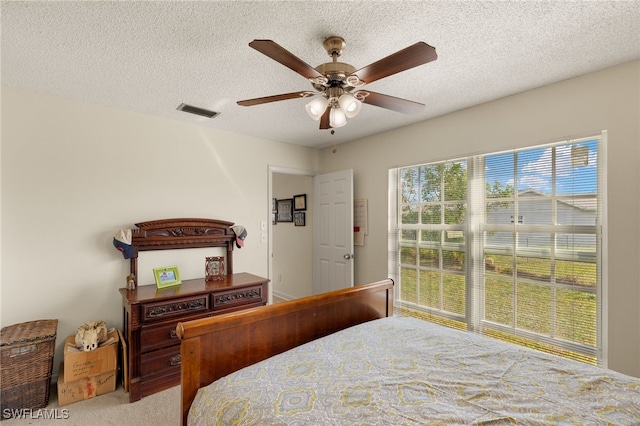 carpeted bedroom with ceiling fan and a textured ceiling