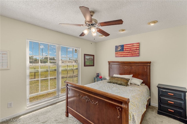 carpeted bedroom featuring ceiling fan and a textured ceiling