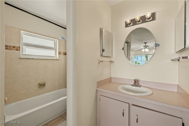 bathroom with tile patterned flooring, tiled shower / bath, plenty of natural light, and vanity