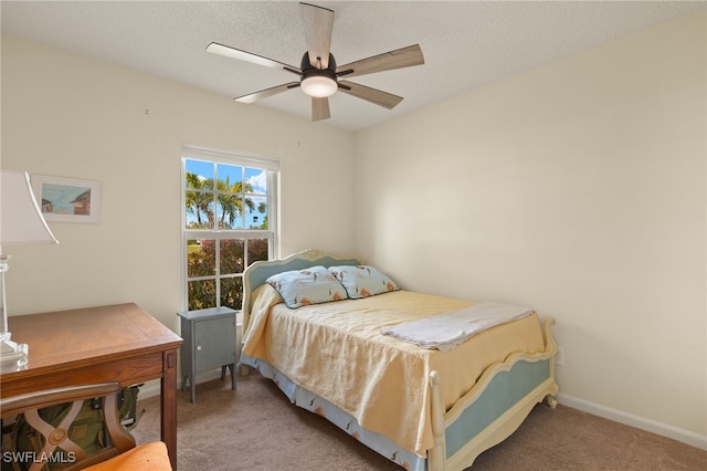 carpeted bedroom featuring ceiling fan and a textured ceiling