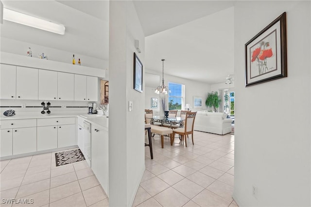 kitchen featuring sink, white cabinetry, light tile patterned floors, a notable chandelier, and pendant lighting