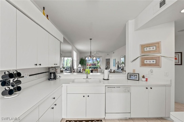 kitchen with white dishwasher, a chandelier, sink, and white cabinets