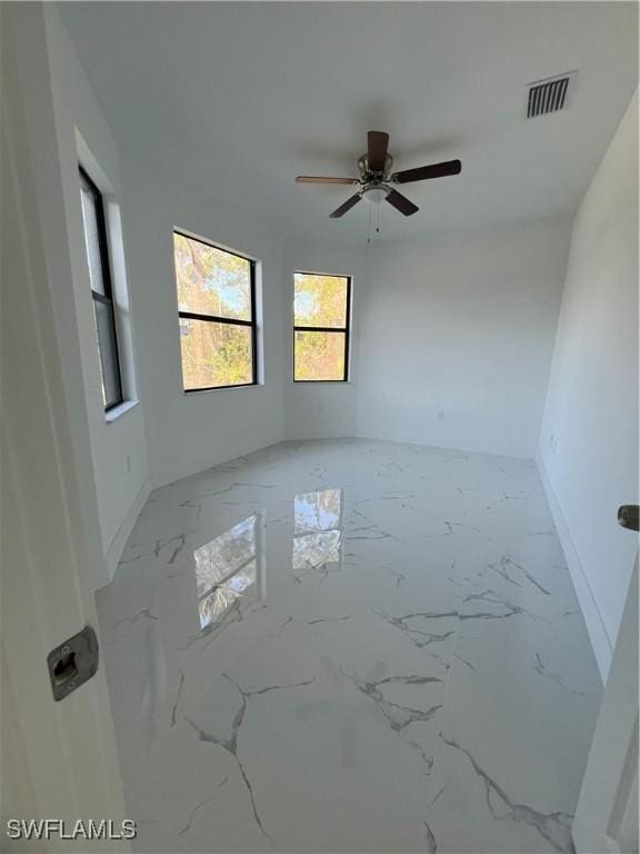 unfurnished room with marble finish floor, visible vents, and baseboards