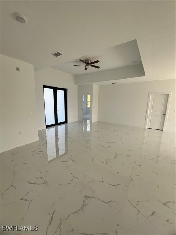 spare room featuring a ceiling fan, visible vents, baseboards, marble finish floor, and french doors