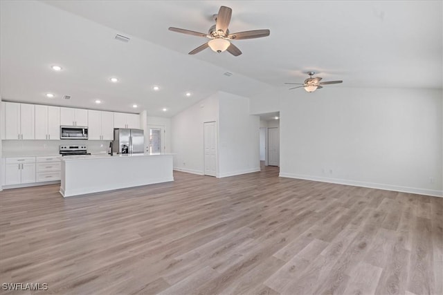 unfurnished living room with lofted ceiling, sink, ceiling fan, and light wood-type flooring