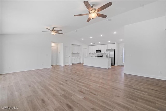 unfurnished living room featuring vaulted ceiling, sink, ceiling fan, and light wood-type flooring