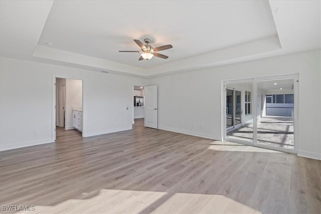 unfurnished room with light hardwood / wood-style floors, a raised ceiling, and ceiling fan